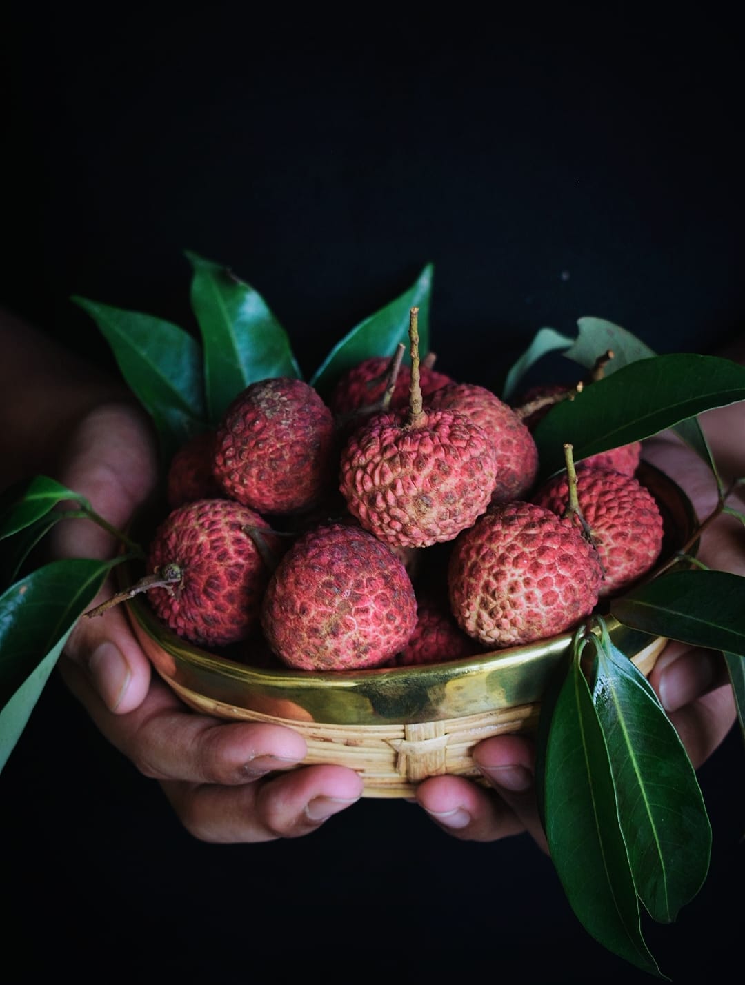 A hand holding a Lychee fruit